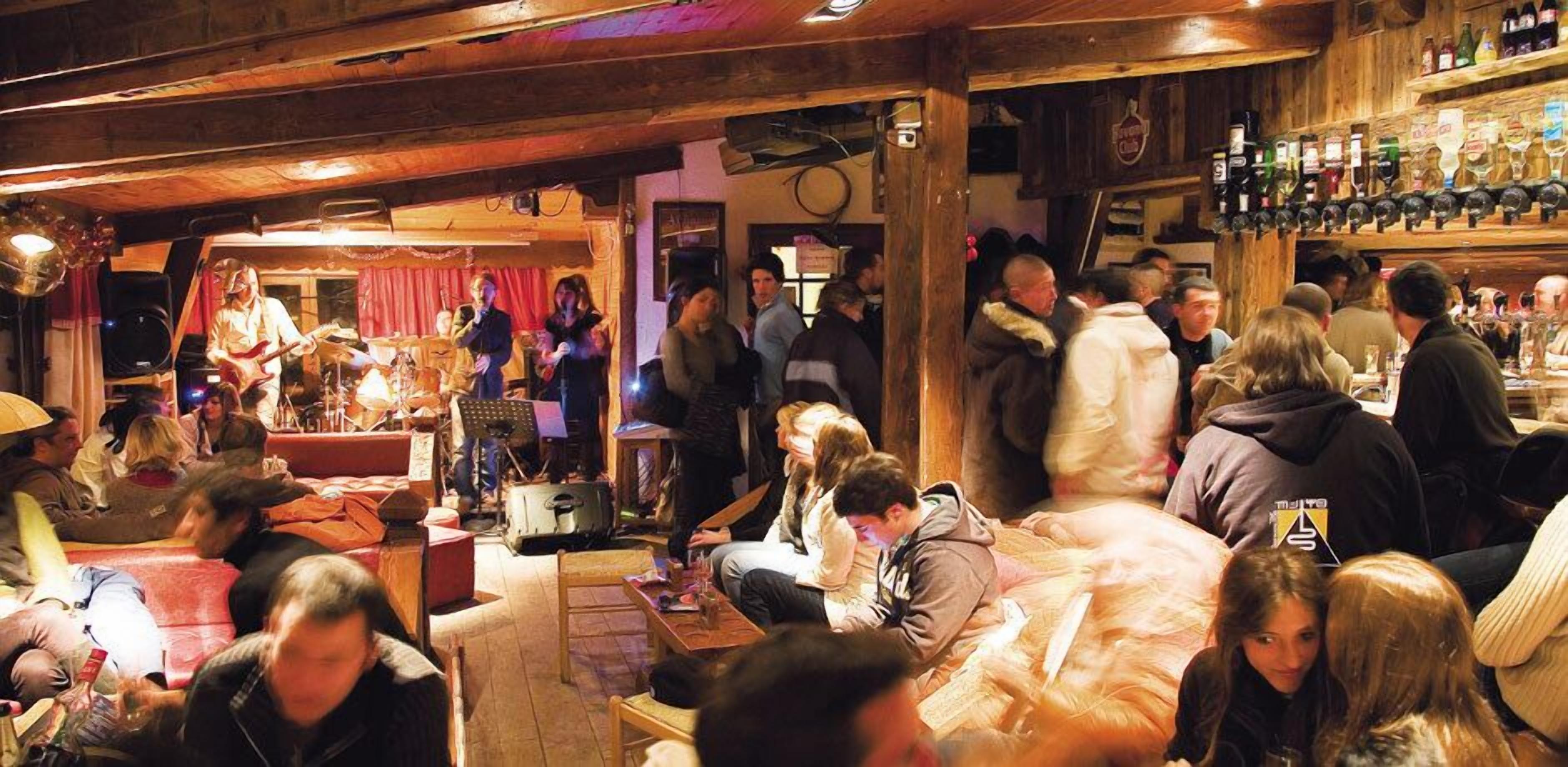 Un bar animé, avec un décor intérieur en bois et une scène pour des concerts.