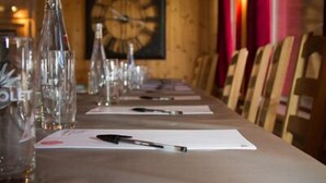 A long table set for a meeting with documents, pens, and water bottles. - Hôtel Les Escondus (Vars)