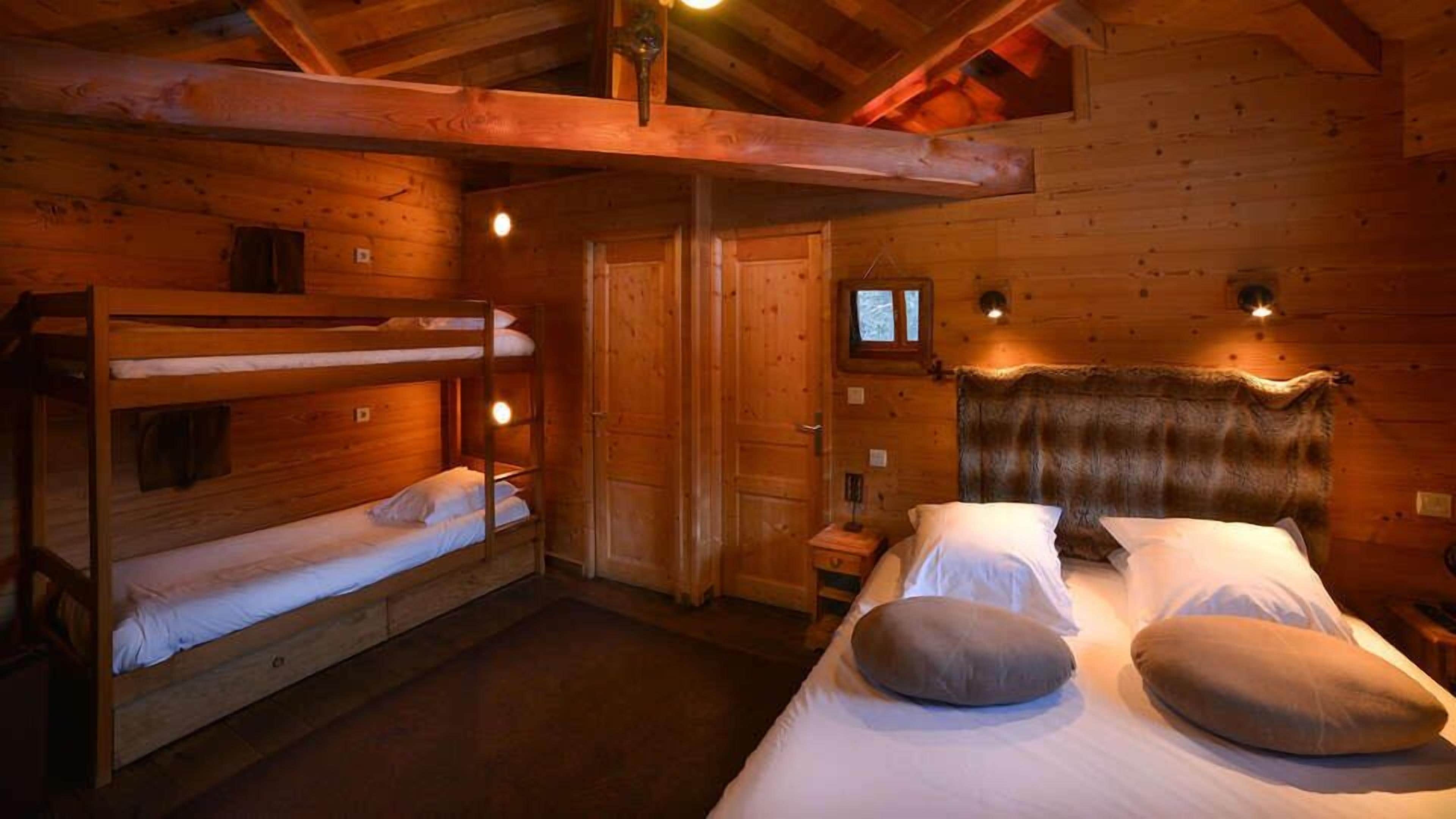 Quarto estilo cabana, com paredes de madeira e uma cama beliche à esquerda.