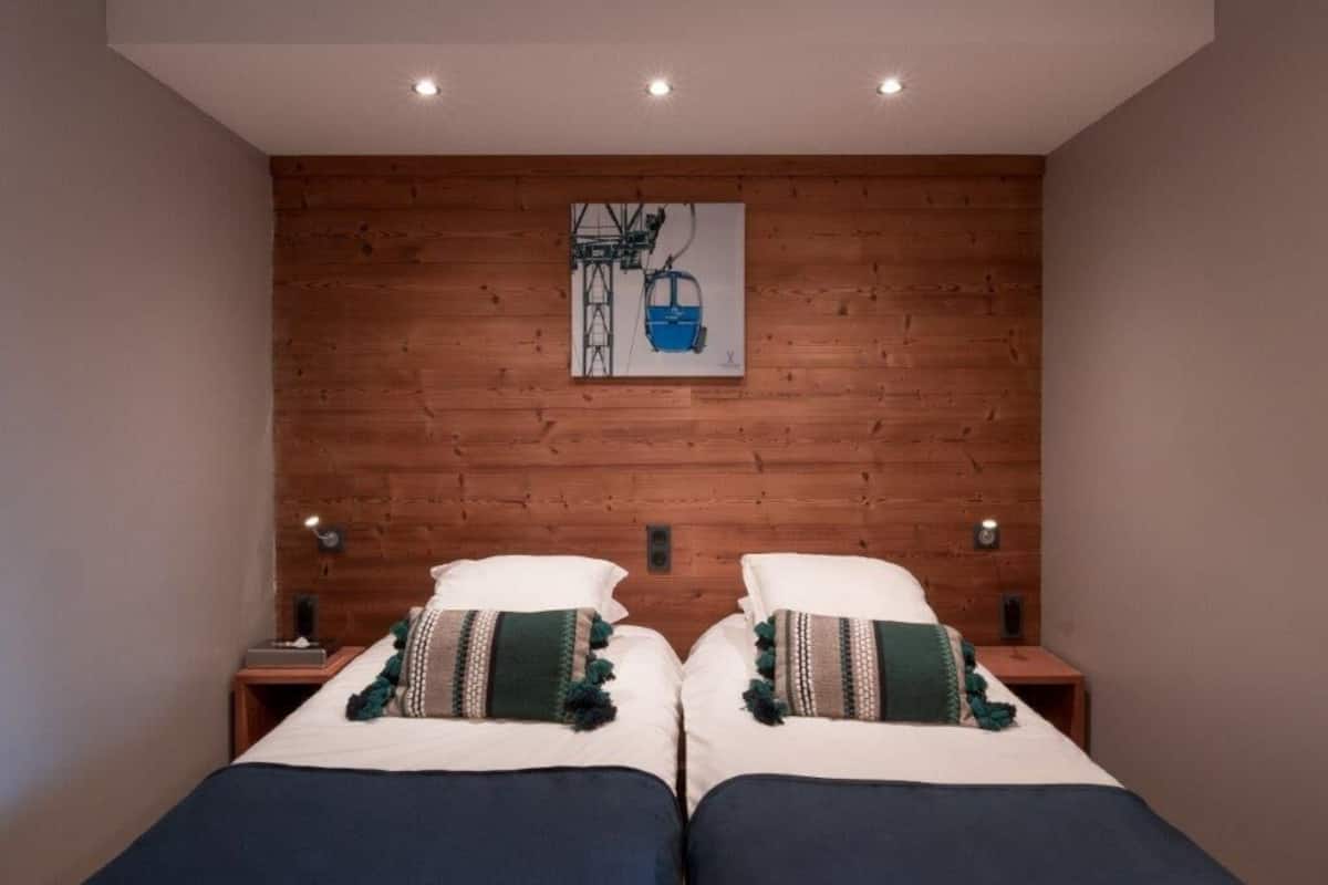 A double bed with two nightstands, a wooden headboard, and a wall-mounted painting of a cable car.