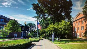 A paved pathway with a flag, a building, and greenery. - Quality Inn & Suites Caldwell I-77 (Caldwell)