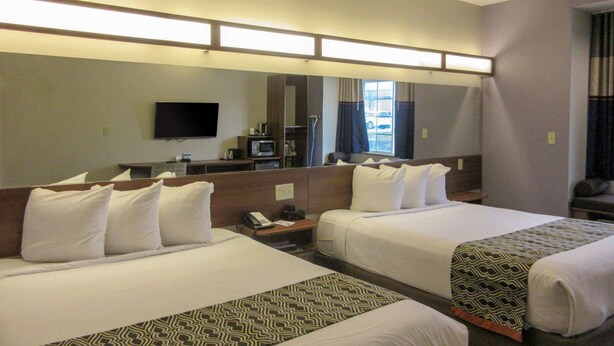 A hotel room with two beds, a TV, a desk with a phone, and a window with curtains. - Quality Inn & Suites Caldwell I-77 (Caldwell)