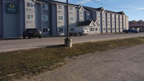 A hotel with a row of rooms, a covered parking area, and a small building with a sign. - Quality Inn & Suites Caldwell I-77 (Caldwell)