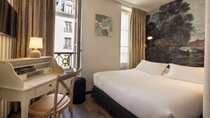 Ein Hotelzimmer mit Bett, Schreibtisch, Stuhl und einem Gemälde an der Wand.