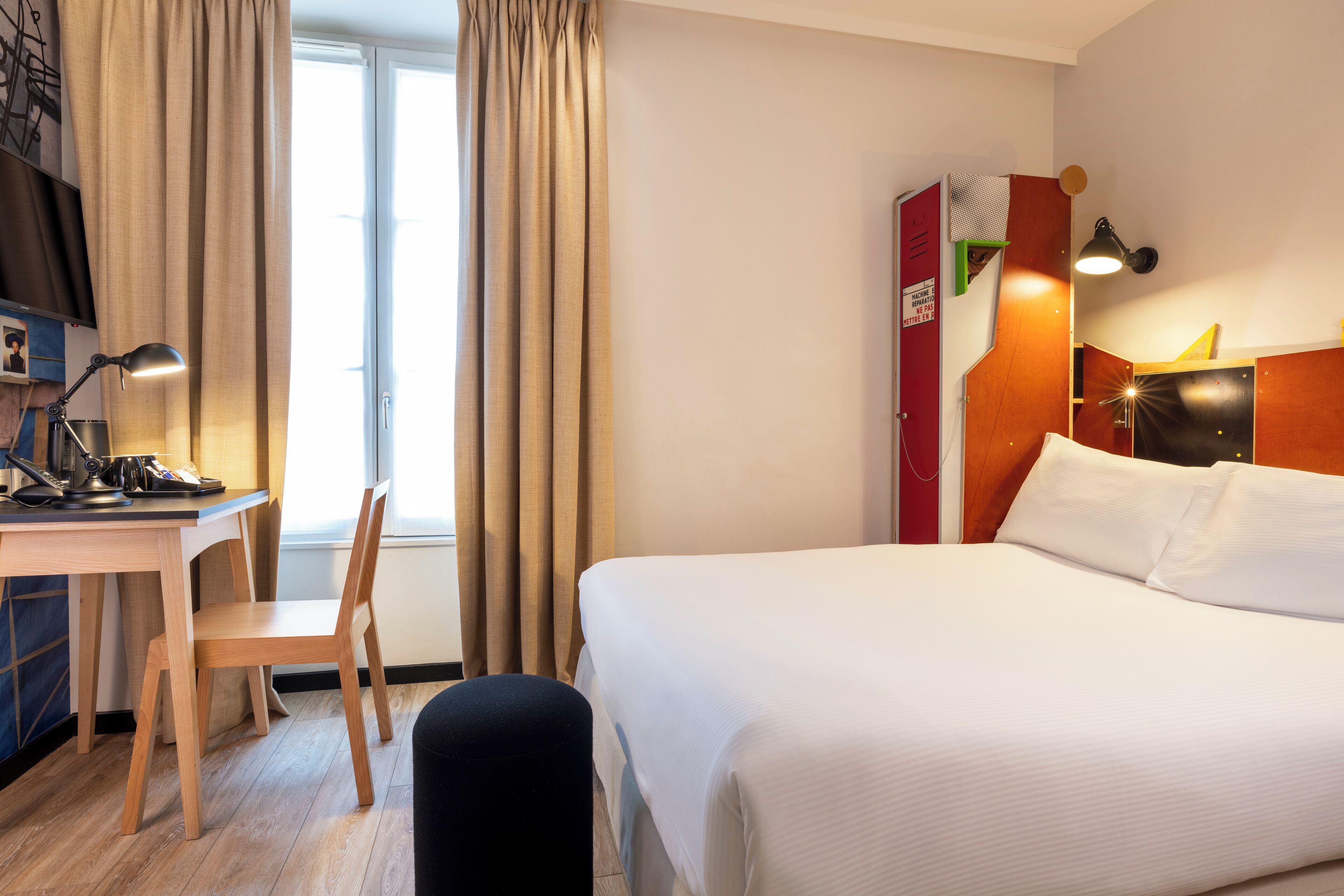 A hotel room with a bed, a desk, a chair, and a wardrobe.