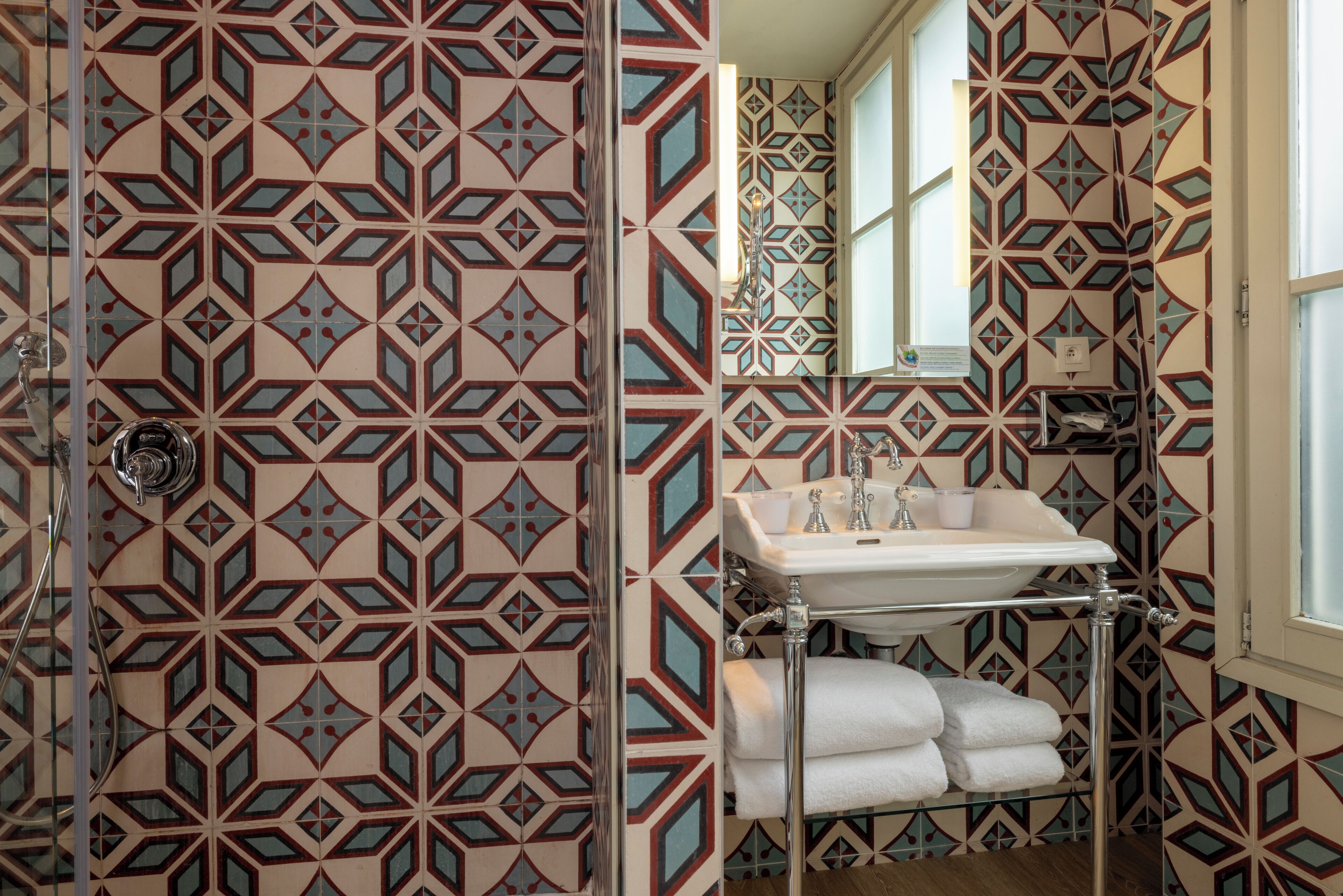 Un baño con papel tapiz estampado, un lavamanos y un perchero para toallas.