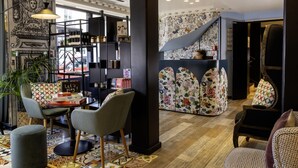 Ein modernes Interieur mit einer zentralen Sitzecke, einem dekorativen Bücherregal und einer Wand mit Muster.