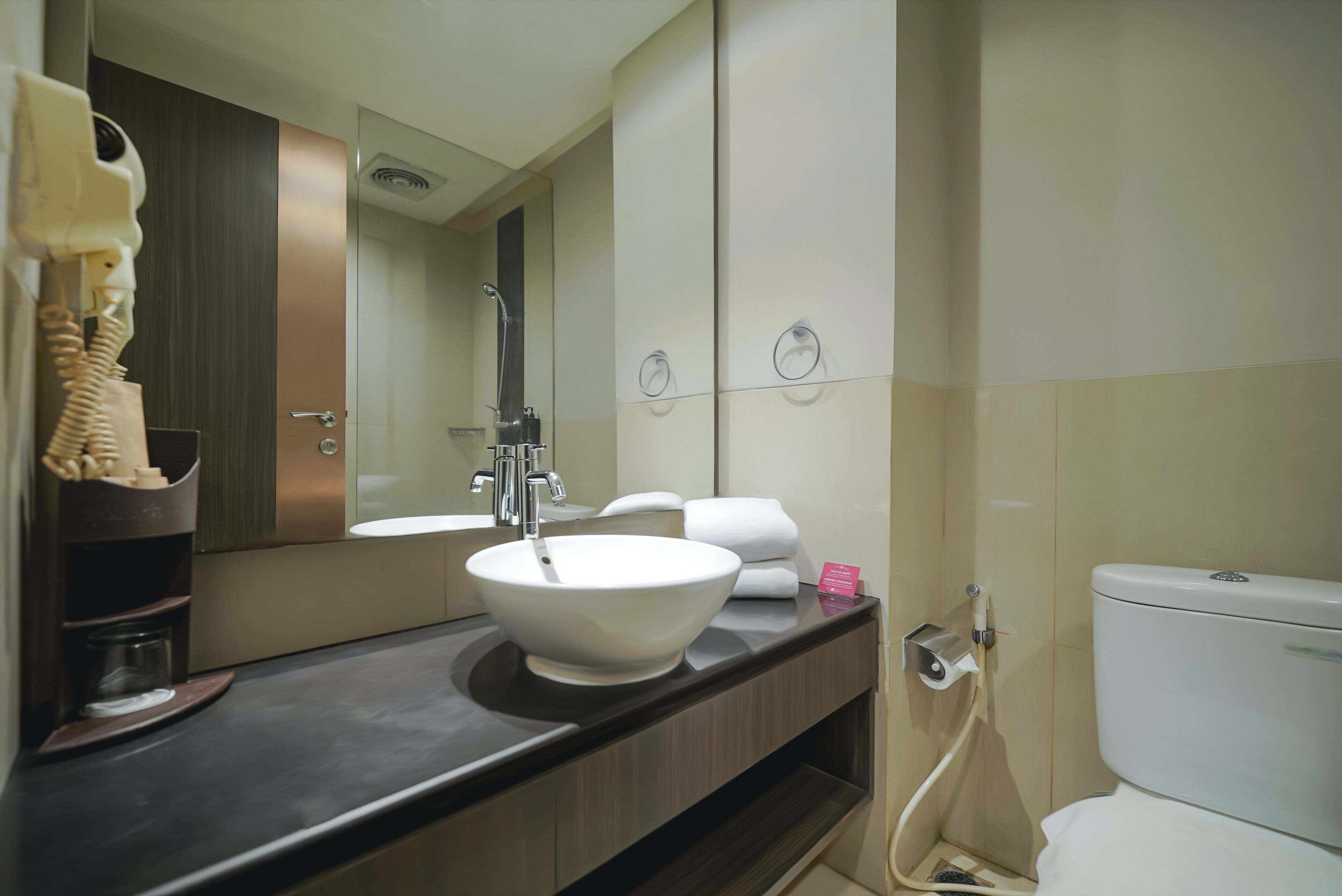 A modern bathroom with a large mirror, a white sink, a toilet, and a shower.