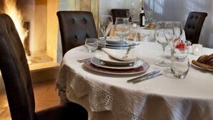 Een eetkamer met een open haard, een tafel gedekt voor vier personen en een kroonluchter.