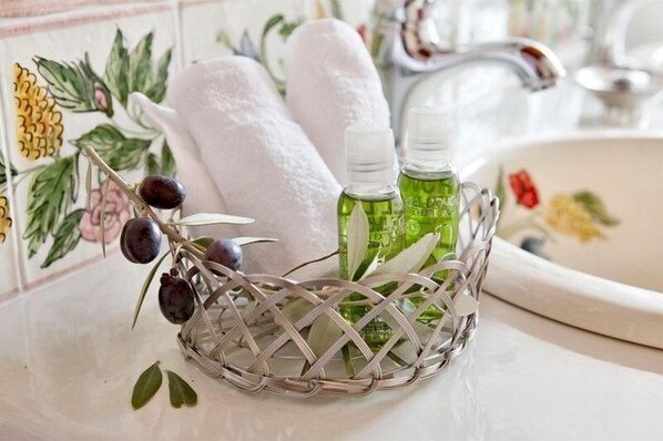 A bathroom with a decorative metal basket containing toiletries, a white towel, and a bottle of green liquid soap.