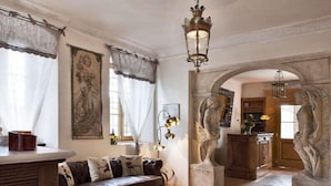 Een ruime woonkamer met een leren bank, een eethoek met een houten tafel, en een stenen boog die naar een andere kamer leidt.