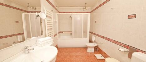 Un baño con bañera, inodoro, lavabo y espejo.