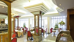 Ein Restaurant mit Marmorplatten, roten Stühlen und weißen Tischdecken.