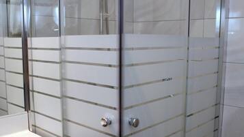 Cabina de ducha con paredes de azulejos blancos y ducha de acero cromado.