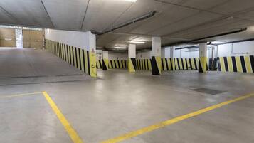 Un estacionamiento de varios niveles con barreras a rayas amarillas y negras, pilares de hormigón y una rampa que conduce a un nivel superior.