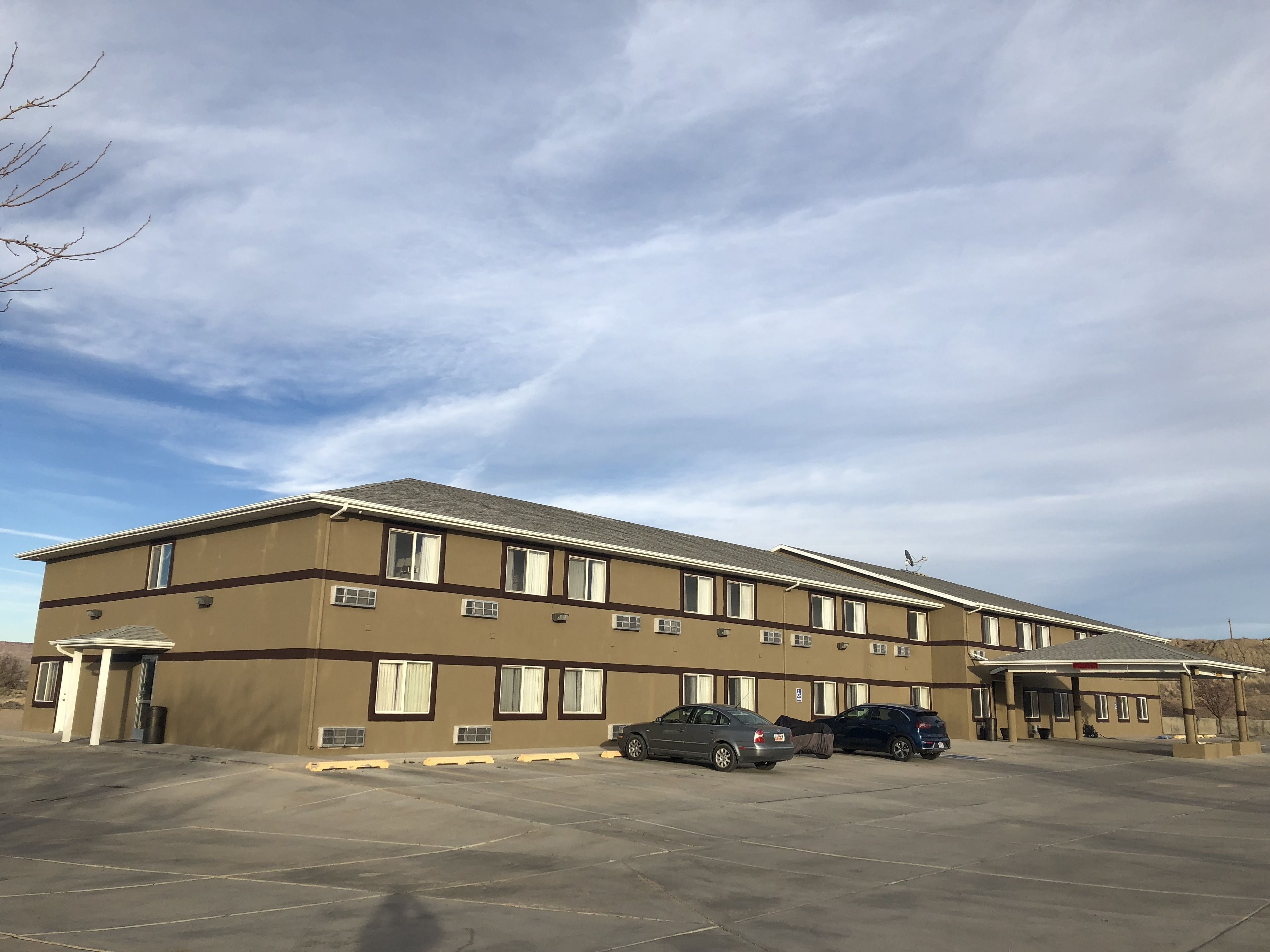 A multi-story building with a flat roof and a parking lot in front.
