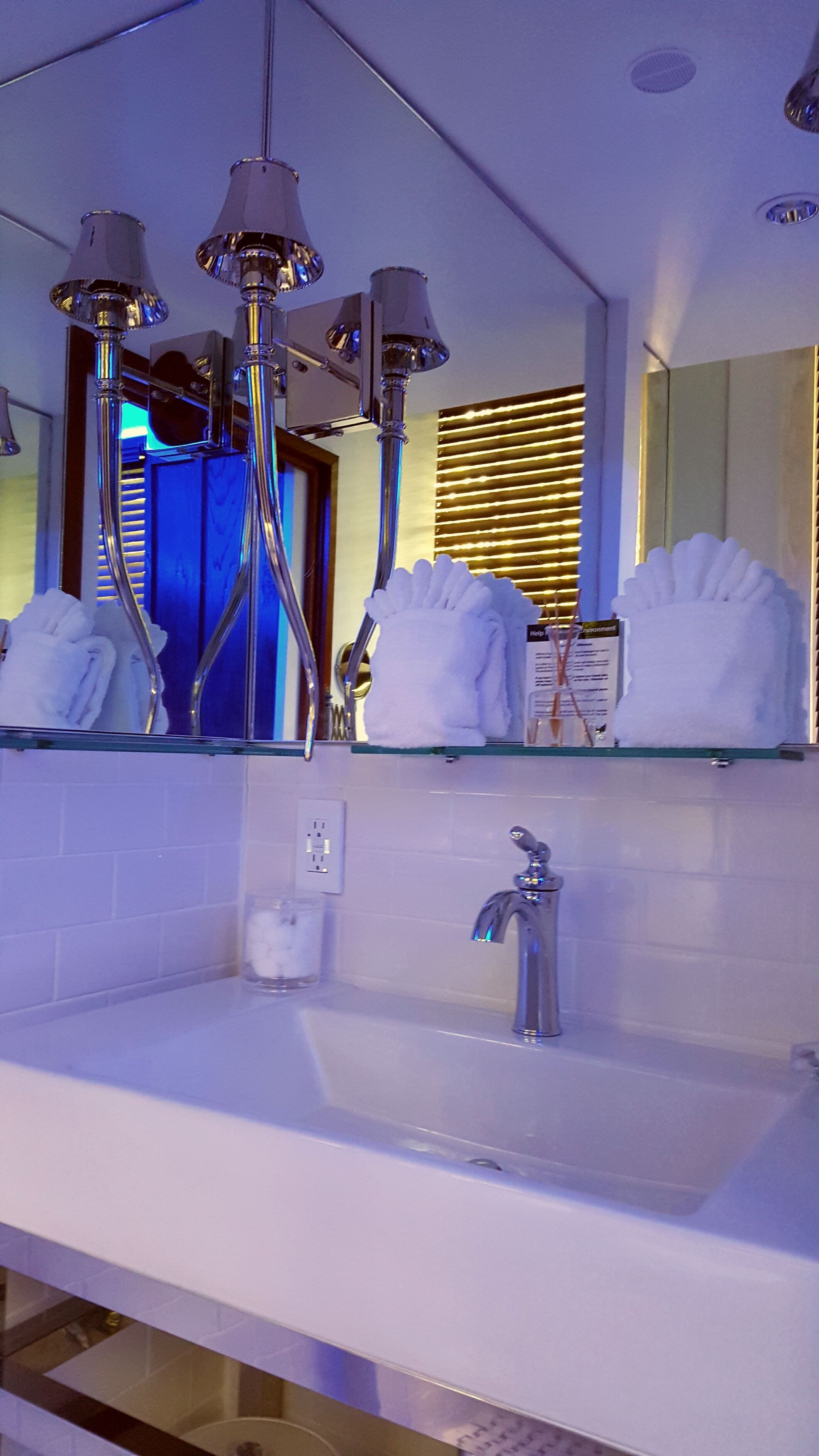 Une salle de bain moderne avec un lavabo blanc, des robinetteries chromées et un miroir au-dessus.