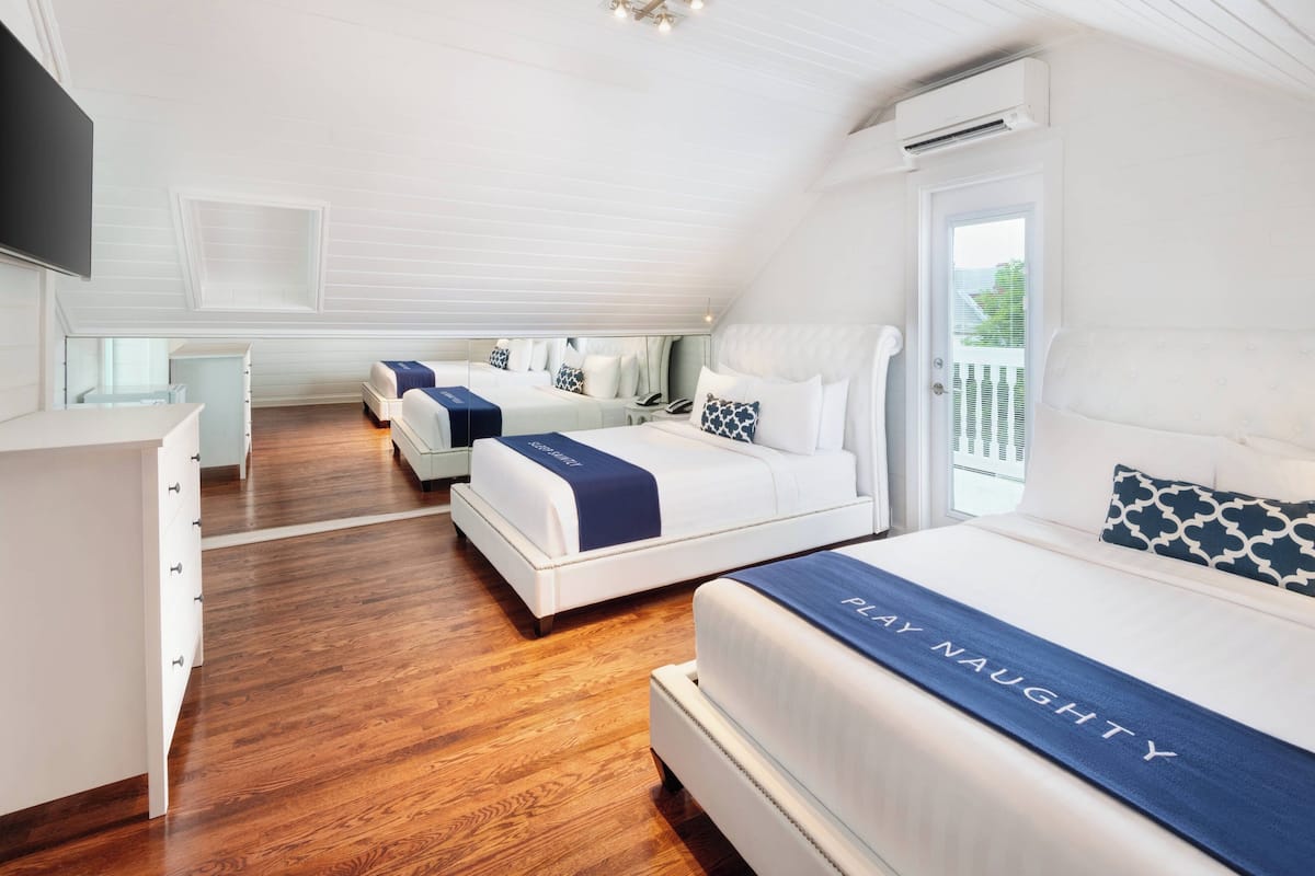 A hotel room with two beds, a desk, and a large window.