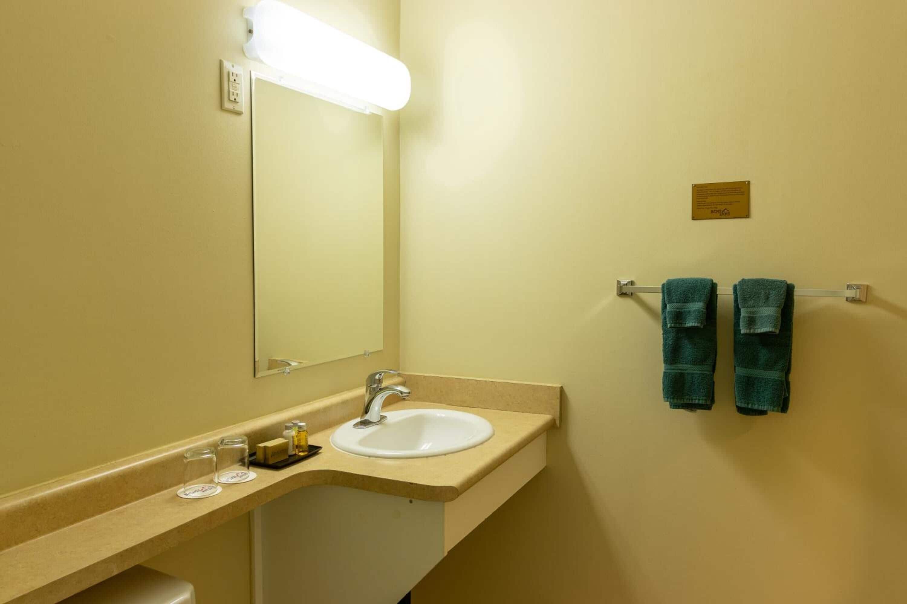 Een badkamer met een wastafel, spiegel en handdoekhouder.