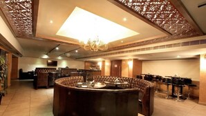 A circular bar area with seating, a chandelier, and a television mounted on the wall. - Best Western Ashoka (Hyderabad)