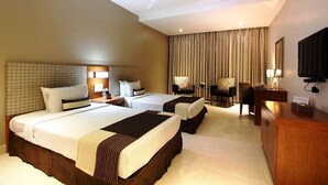 A hotel room with two beds, a desk, a chair, a television, and a ceiling fan. - Best Western Ashoka (Hyderabad)