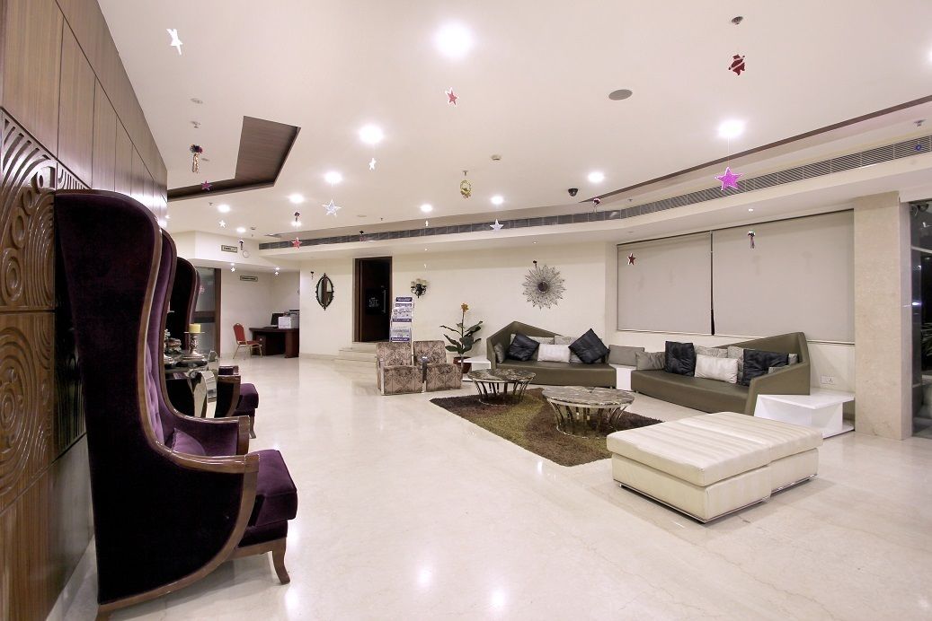 Eine geräumige Lobby mit modernem Design, ausgestattet mit einem violetten Sessel, Sofas, einem Couchtisch und einem weißen Hocker.