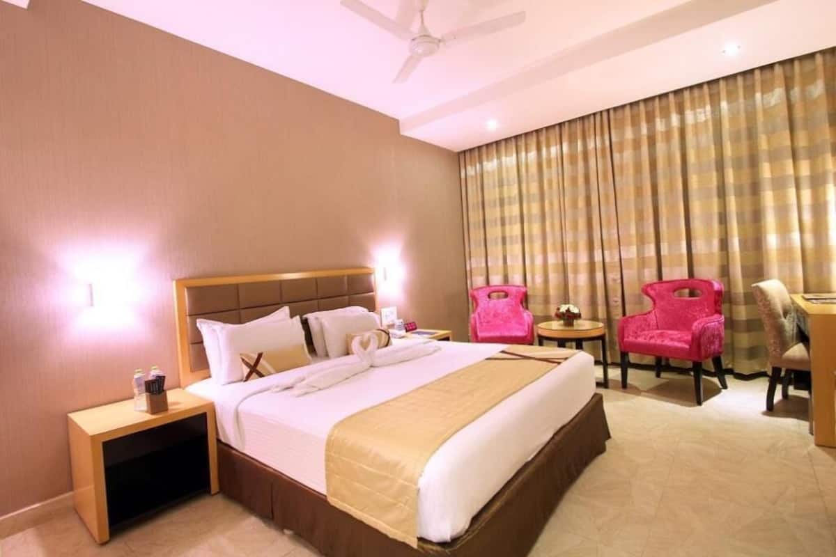 A hotel room with a bed, a nightstand, a desk, a chair, and a ceiling fan.