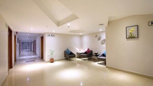A hotel lobby with a long corridor, a reception desk, and seating area with chairs and a potted plant. - Best Western Ashoka (Hyderabad)