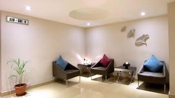 A modern waiting area with three armchairs, a small table, and a potted plant.