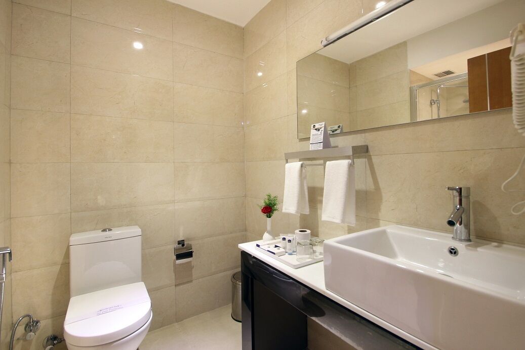A modern bathroom with a toilet, sink, and mirror.