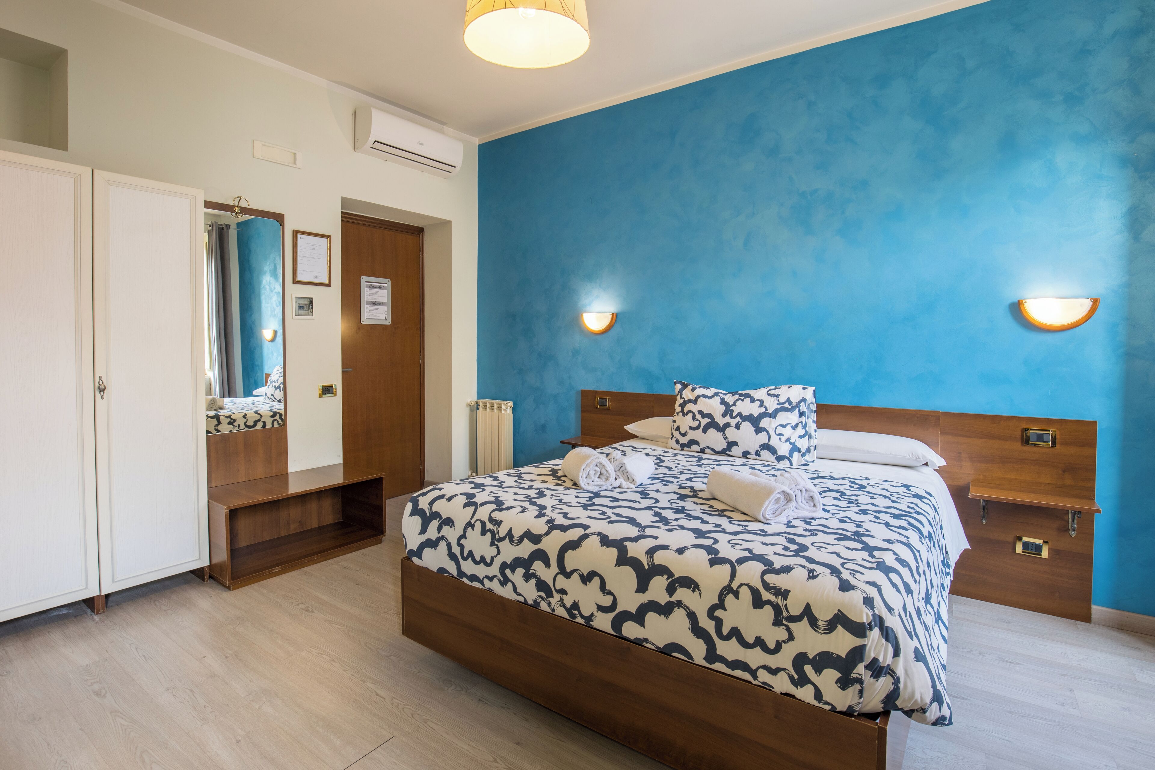 A bedroom with a bed, bedside tables, a wardrobe, and a blue accent wall.
