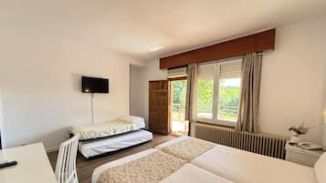 Un dormitorio con dos camas, un escritorio, un televisor y una ventana con cortinas.