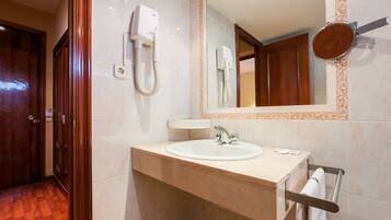 Un baño con lavabo, espejo, toallero y secador de pelo.