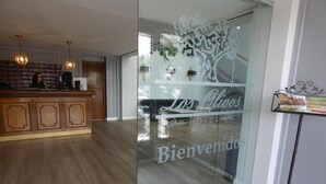 A hotel reception area with a wooden counter, a glass door with 'Los Olivos Hotel' signage, and a modern interior design. - Hotel Los Olivos (Getafe)