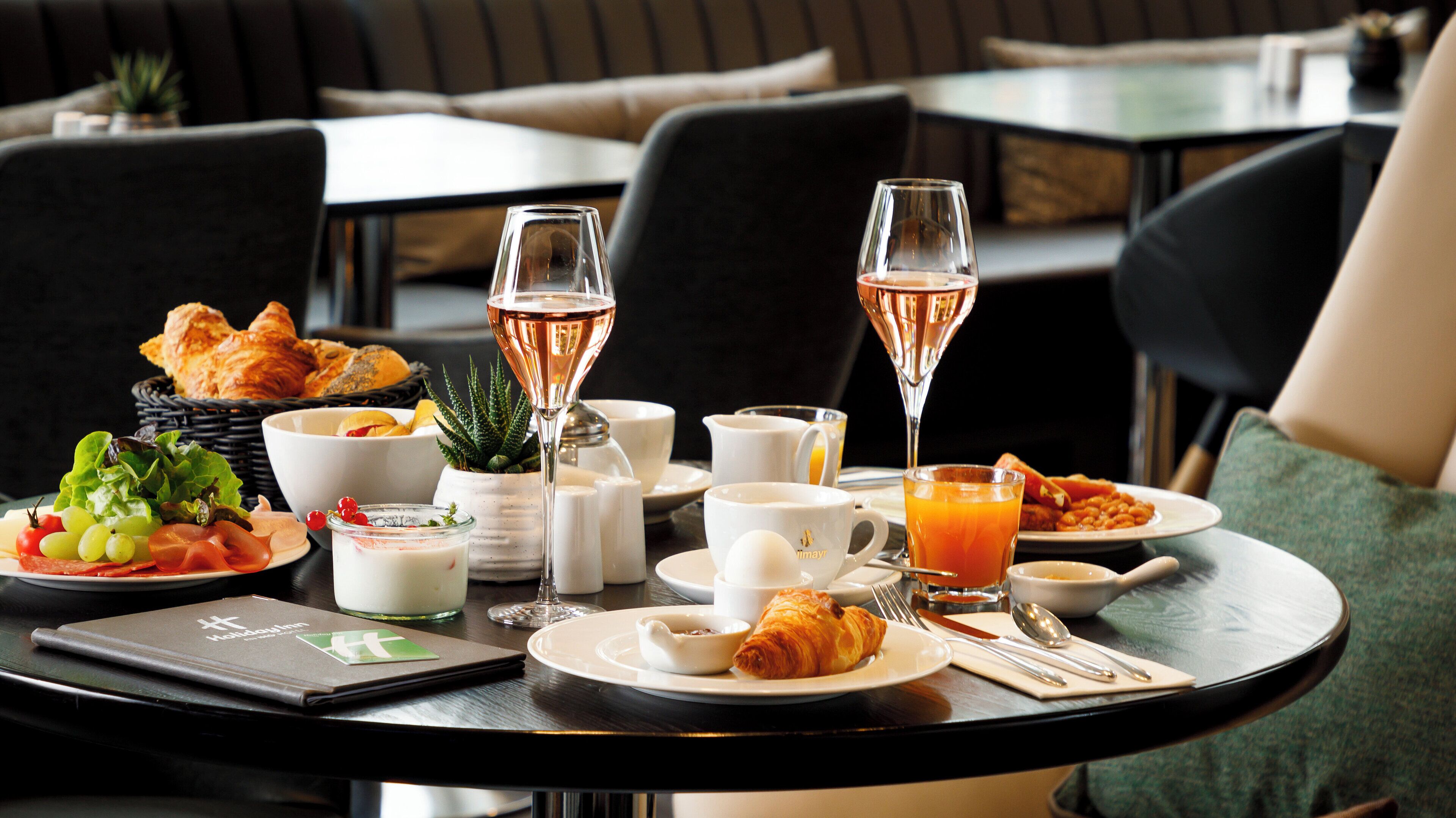 A breakfast setting with croissants, pastries, and a variety of beverages including champagne.
