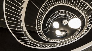 A spiral staircase with a central light fixture and three spherical lights. - Holiday Inn Dresden - Am Zwinger by IHG (Dresden)
