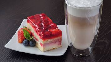 A slice of layered dessert with a red topping and a glass of milk.