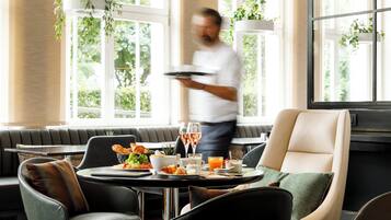 A dining area with a table set for breakfast, including croissants, fruit, and juice.