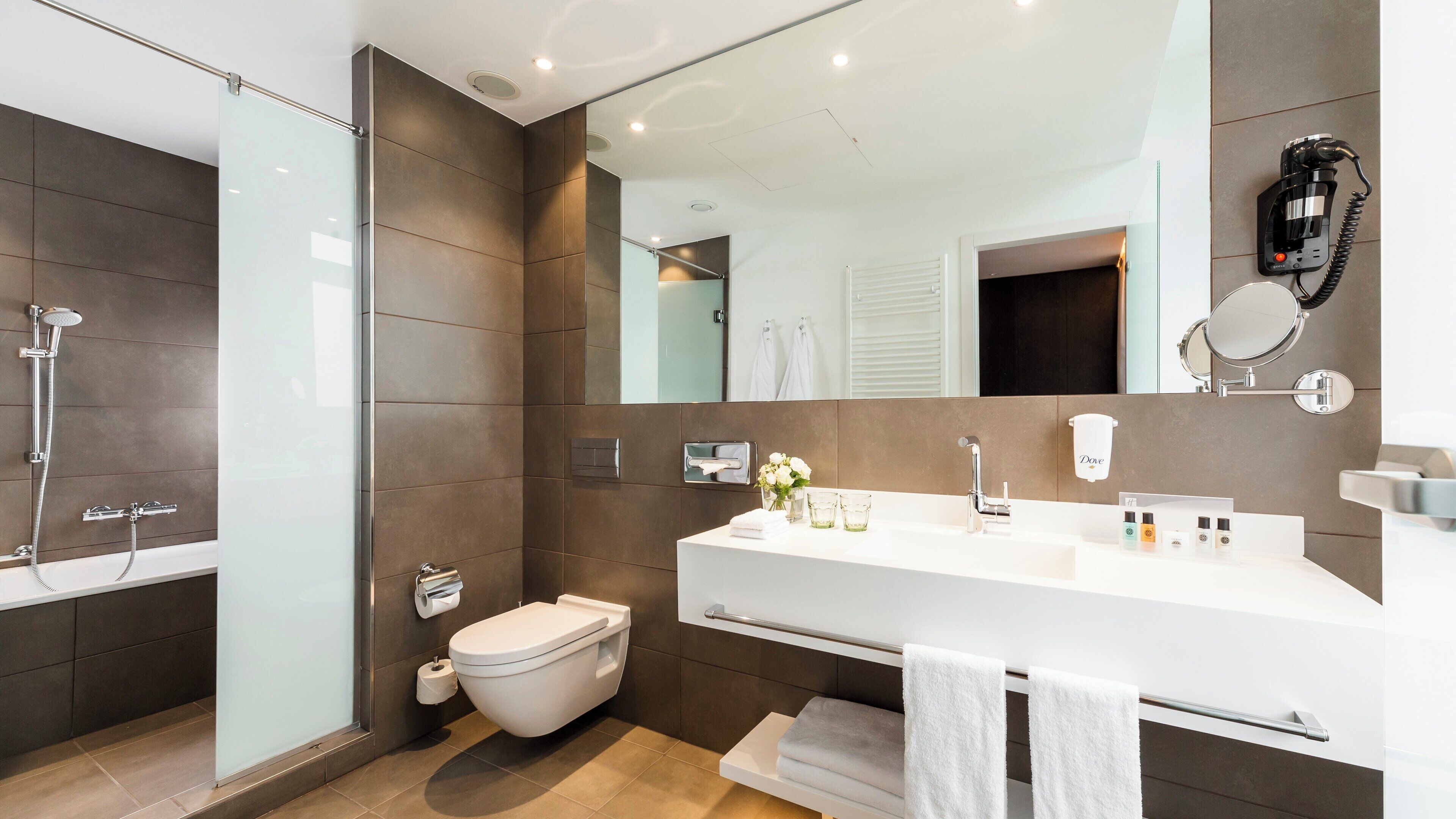 A modern bathroom with a shower, toilet, and vanity.