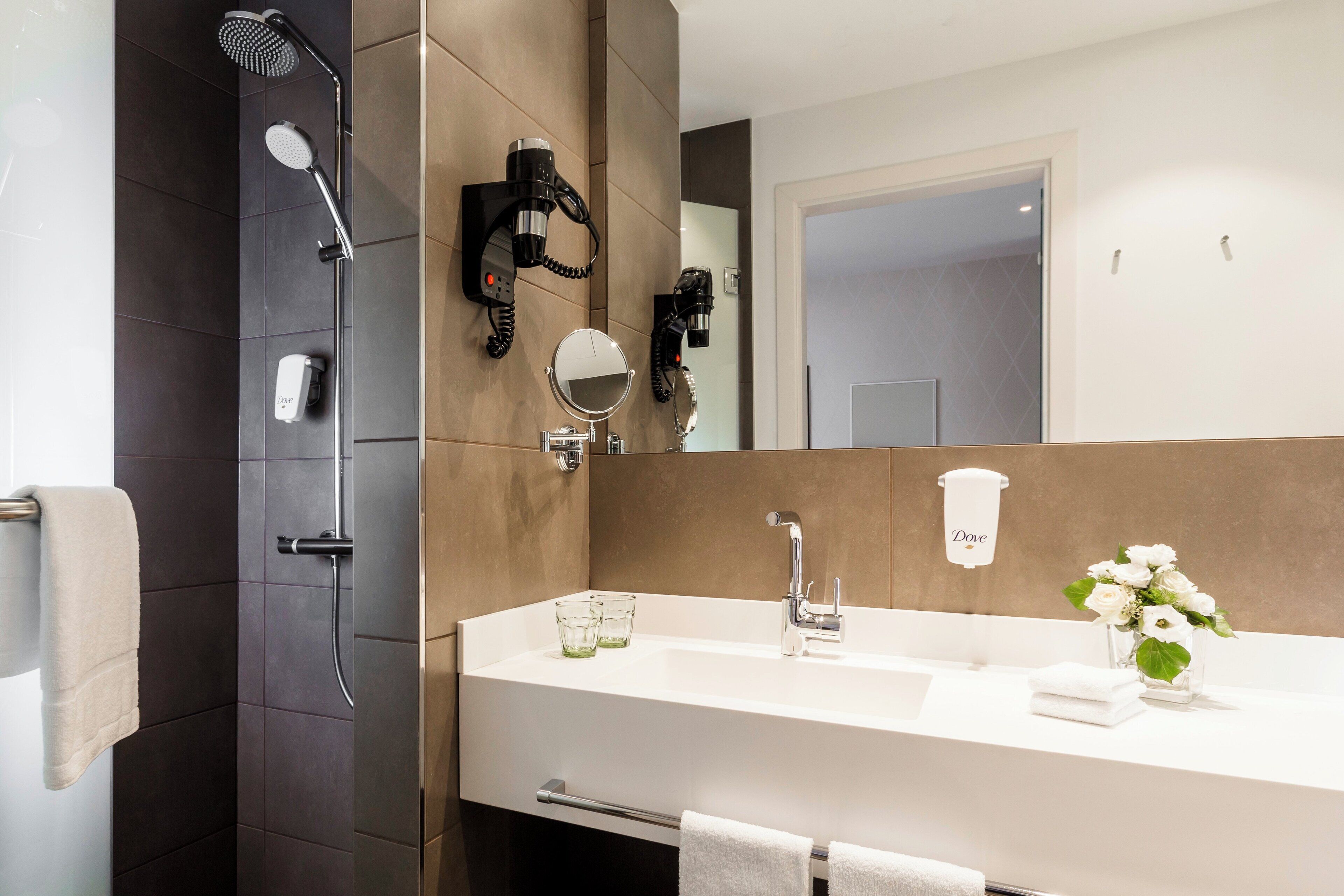 A modern bathroom with a shower, a sink, a mirror, and a towel rack.