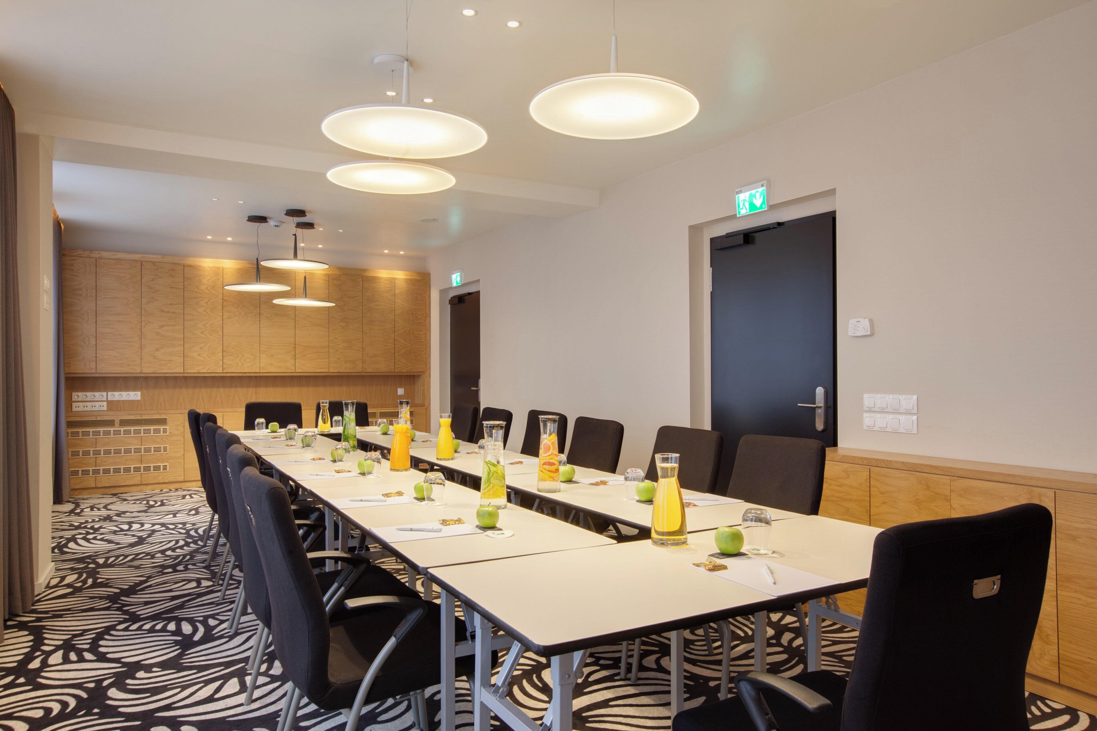 A conference room with a long table, chairs, and overhead lighting.