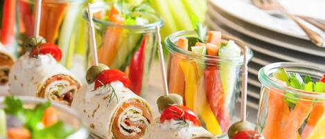 A variety of food items, including wraps and a colorful fruit and vegetable salad, arranged on a table.