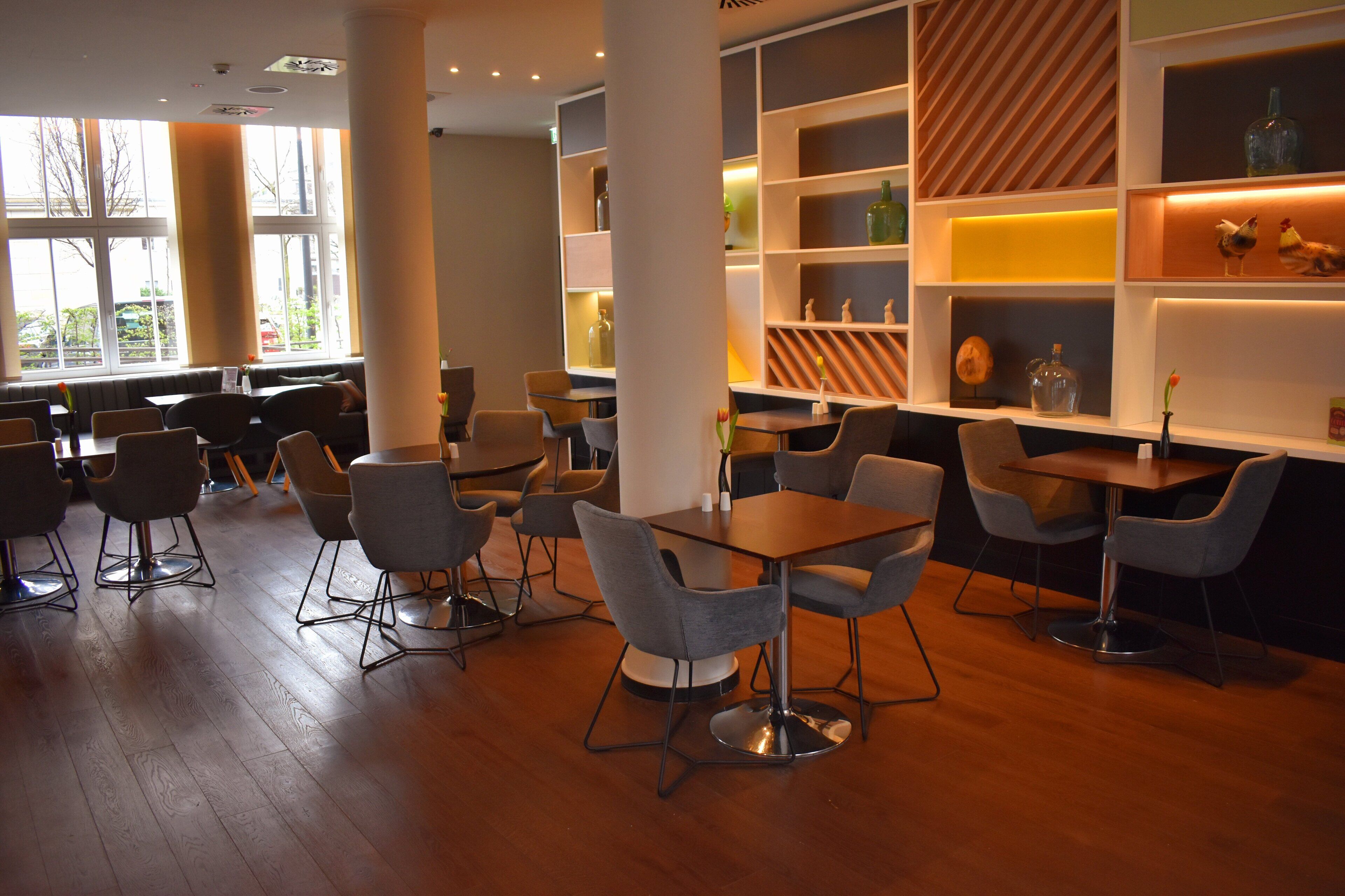 A modern interior with wooden flooring, grey upholstered chairs, and a central table.
