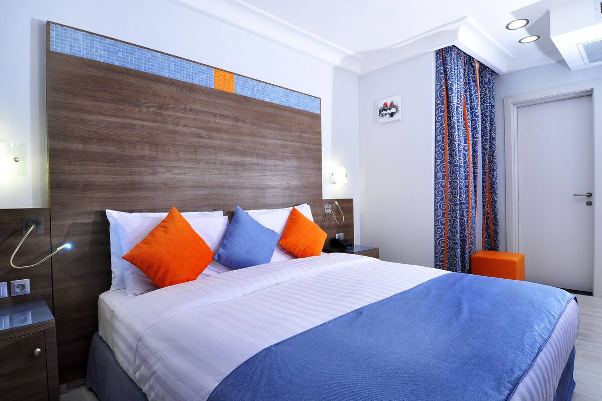 A hotel room with a bed, nightstand, and a bathroom with a shower curtain.