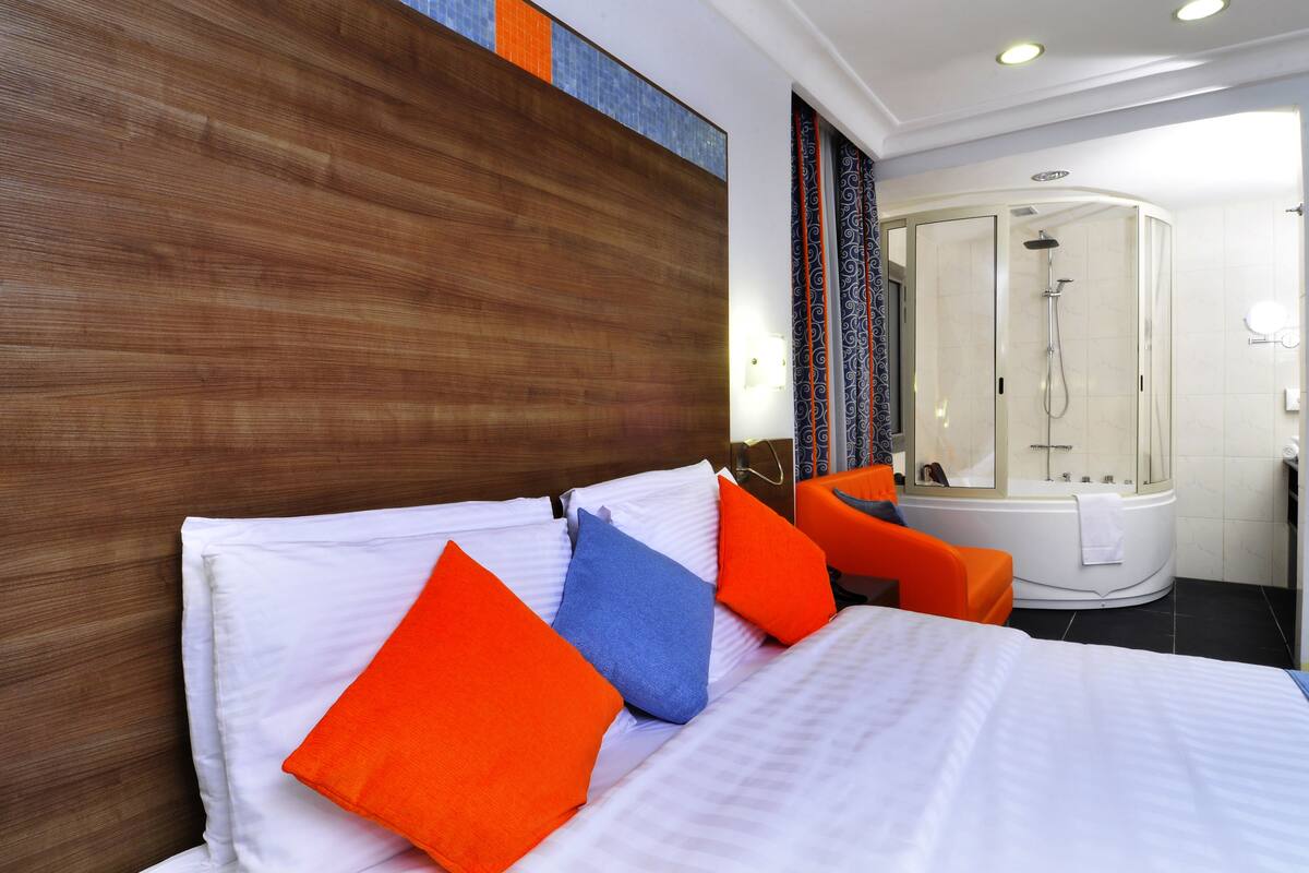 A hotel room with a bed, pillows, a shower, and a bathtub.