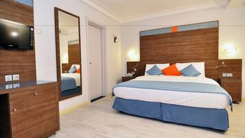 Habitación de hotel con una cama grande, un aparador de madera, un televisor de pantalla plana y un espejo.