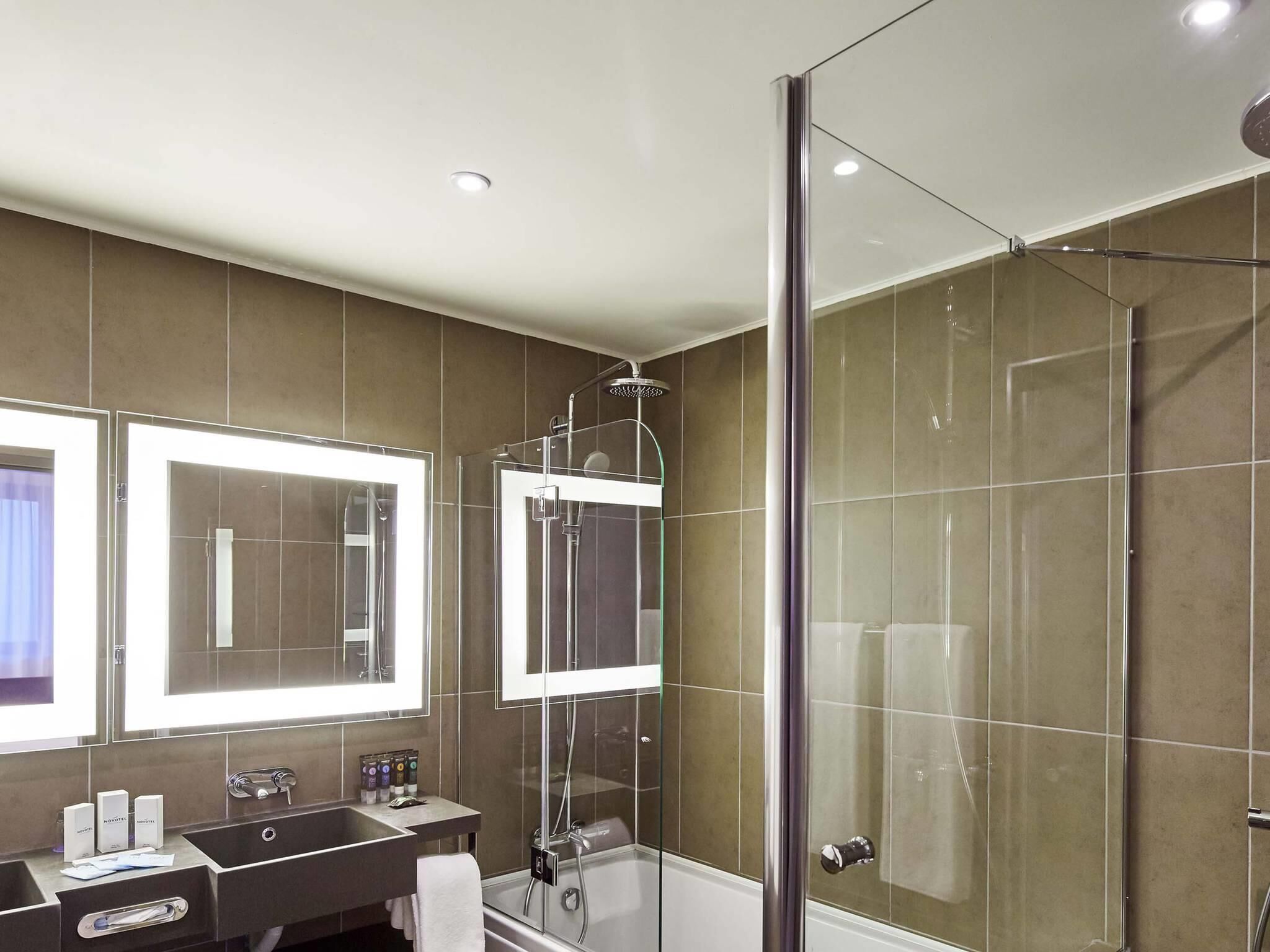 Ein modernes Badezimmer mit einer begehbaren Glasdusche, einem Doppelwaschbecken und einem großen Spiegel.