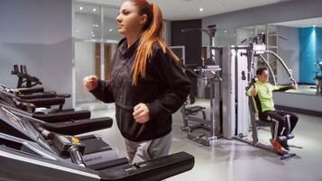 A gym with treadmills, weight machines, and a mirrored wall.