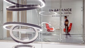 Un interior moderno con una pared de vidrio que muestra el texto 'IN BALANCE BNVOTEL WELLNESS CENTER'.