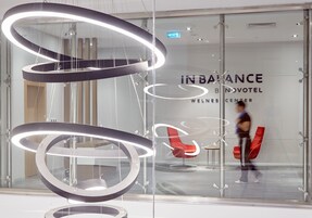 A modern interior with a glass wall displaying the text "IN BALANCE BNVOTEL WELLNESS CENTER".